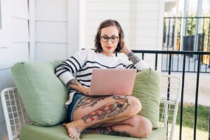 Woman sitting on couch porch working on computer