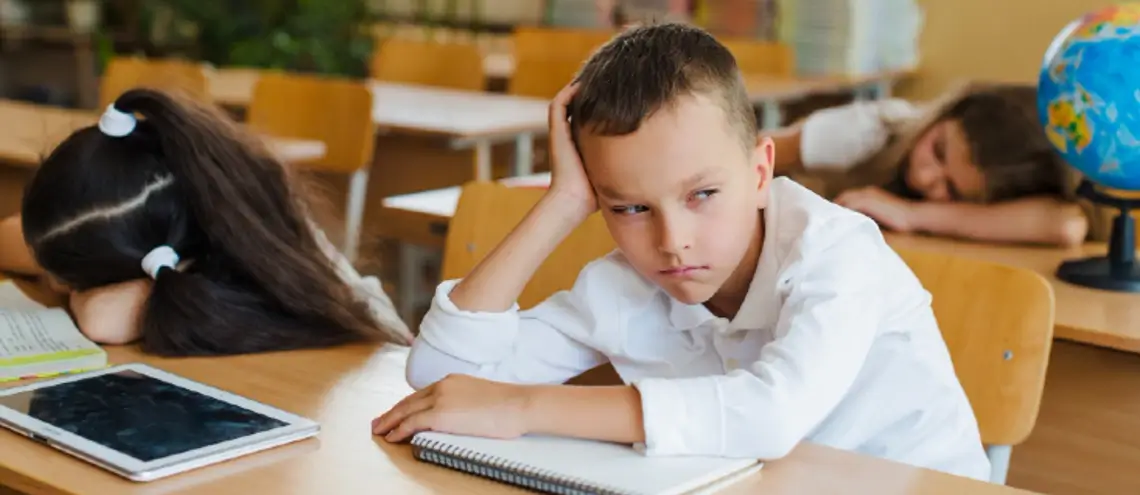 BOY SITTING ON THE DESK LOOK AWAY BORING SCHOOL