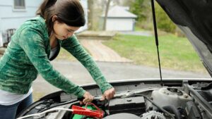 woman showing how to jump a car battery