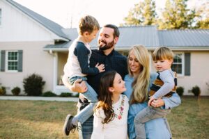 This is an image of a happy family standing in front of their home