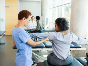 Occupational therapist checks arm alignment on a female patient