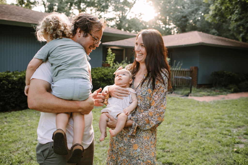 This is an image of an attractive young family hanging out in front of their house