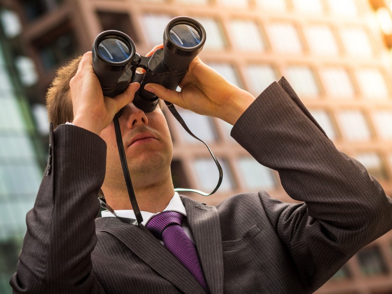 Insurance broker using binoculars to find opportunities