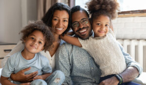 A smiling couple hold their young son and daughter on the couch