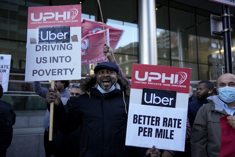 People hold protest signs demanding higher pay from Uber