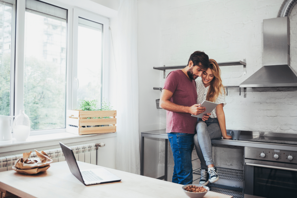 Boyfriend and girlfriend reading from tablet in the kitchen.