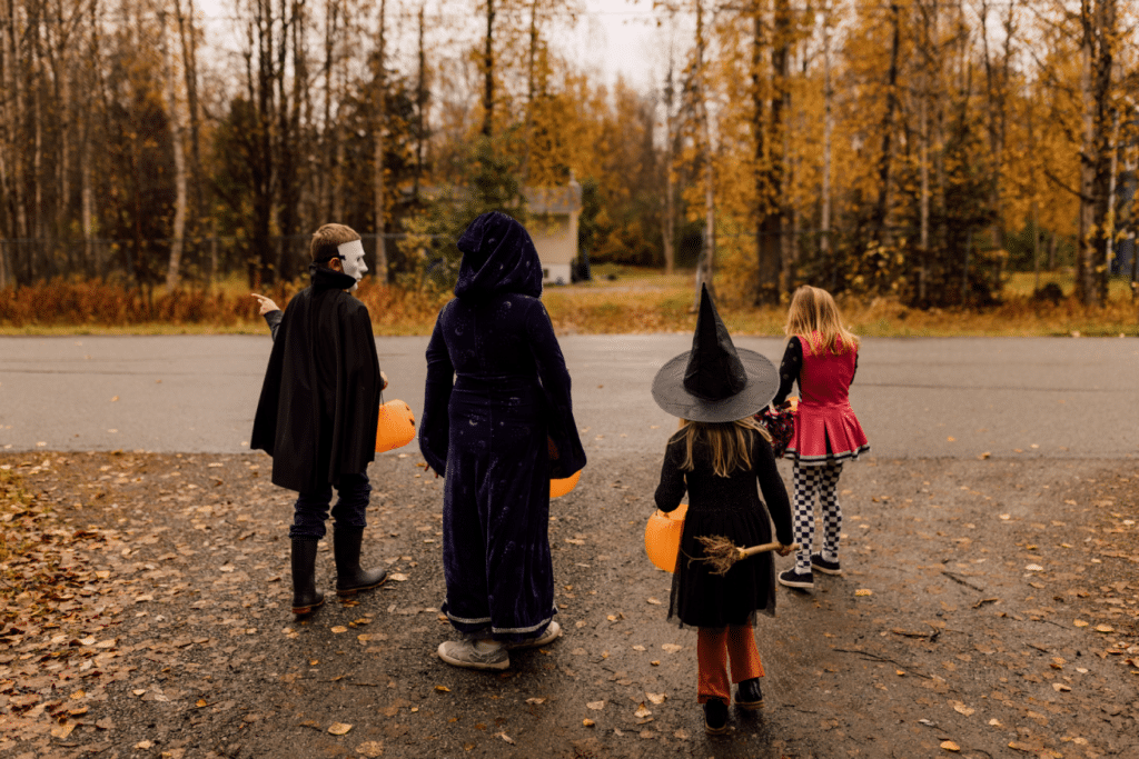 Siblings trick-or-treating with orange pumpkin buckets.