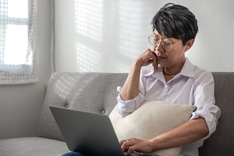 A woman sits at a laptop.