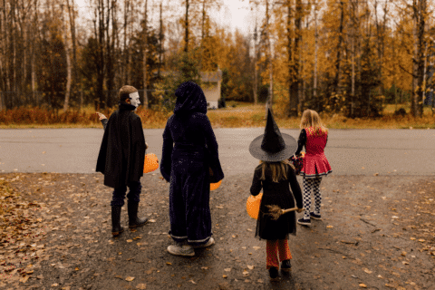 Siblings trick-or-treating with orange pumpkin buckets.