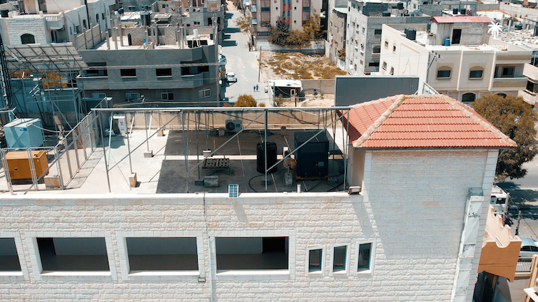 A large cube-shaped machine on the open roof of a building.