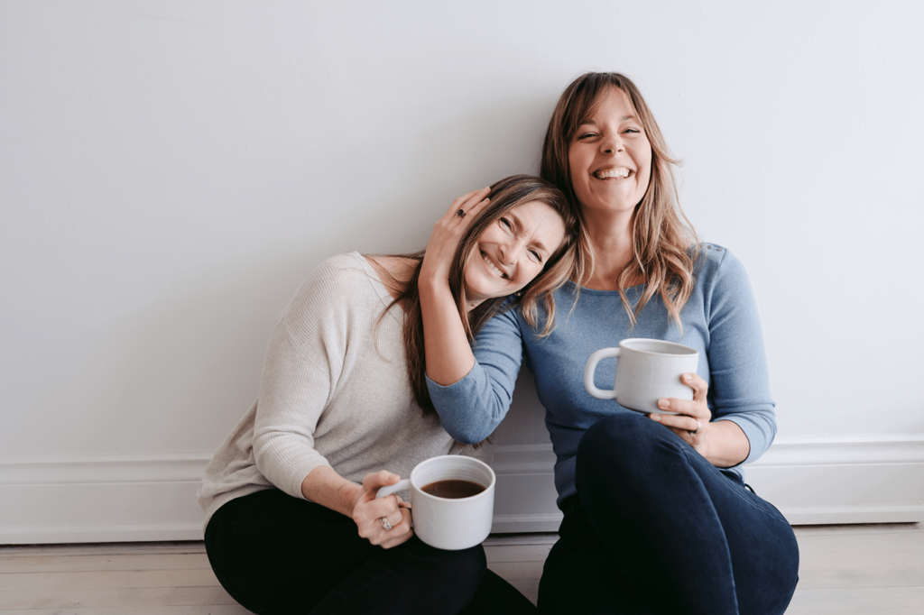 Mother And Daughter As Friends Sitting Together In Empty Room.