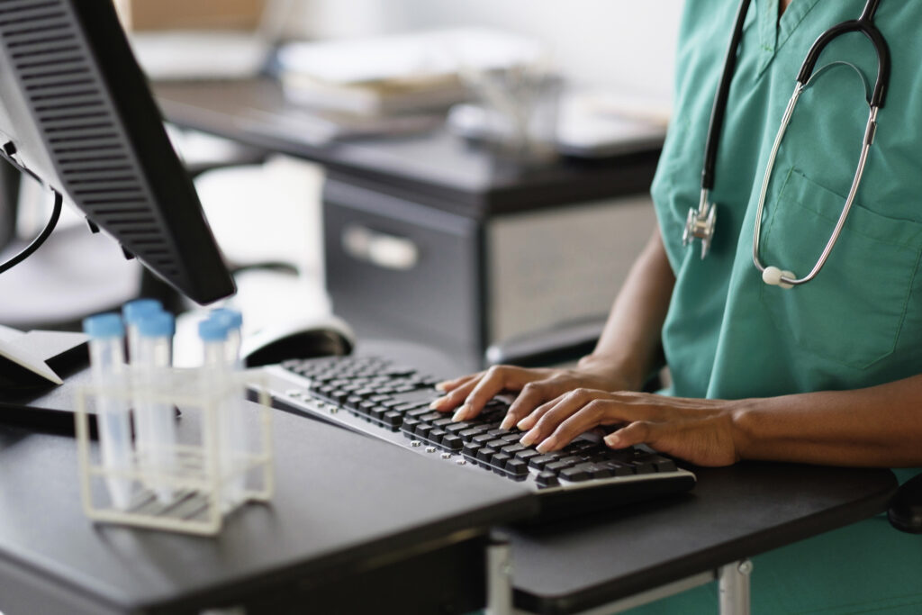 A health worker is typing at a computer.