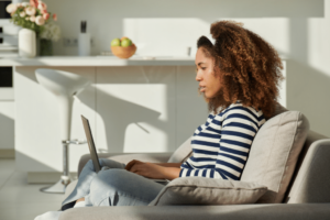 Side view of a serious young pretty woman talking on social networks using laptop and high-speed Internet at home