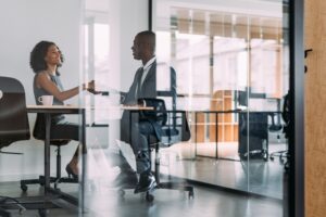 Business people shaking hands in the office. Photo of one cheerful businessman and one happy businesswoman handshaking in the board room. The view is through glass.