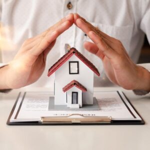 Picture of a modle house on top of a document with hands over it