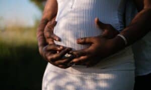 a pregnant belly with the mother and father's hands on it