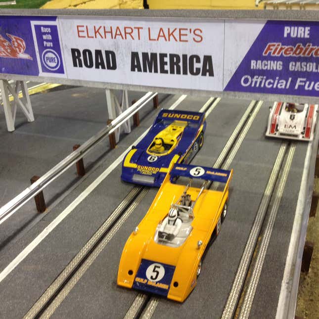 A close up of cars racing on a track made by Slot Mods Raceways. 