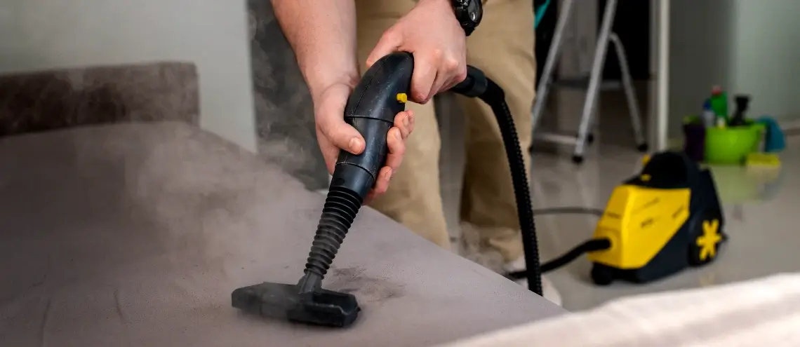 A man vacuuming his bed