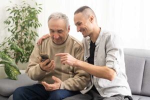 Grown son helping his senior father get a life insurance quote on his phone