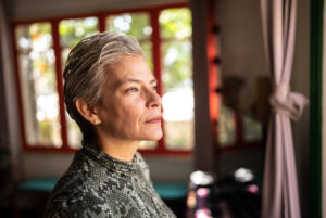 Contemplative mature woman looking through the view at home