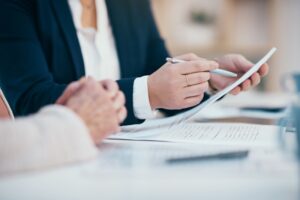 Hands working, reading and writing on business meeting notes in an office boardroom. Closeup view of corporate executive team doing work. Management group looking through finance data together