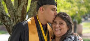 college graduate kissing his mom on the forehead for Quotacy blog My Parents Bought Life Insurance on Me as a Baby. Is It Mine Now?
