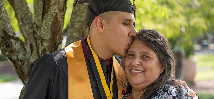 college graduate kissing his mom on the forehead for Quotacy blog My Parents Bought Life Insurance on Me as a Baby. Is It Mine Now?