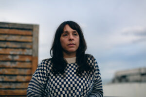 A portrait of a woman outside her apartment.