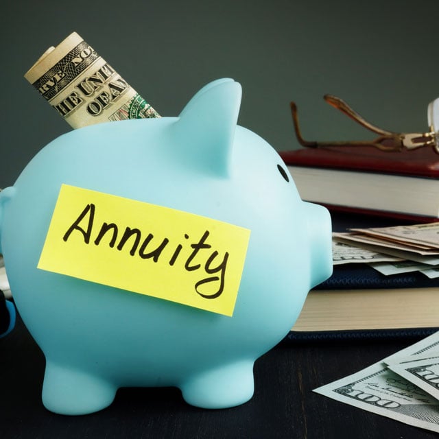 Annuity written on yellow sheet and piggy bank with money.