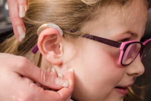 A photo of a person calibrating the hearing aid on a young girl.