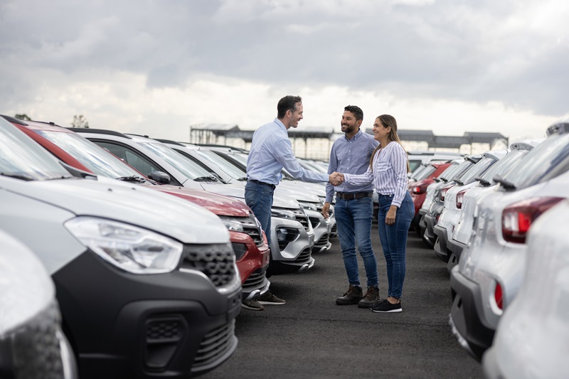 Couple handshaking with a car salesperson after buying a car