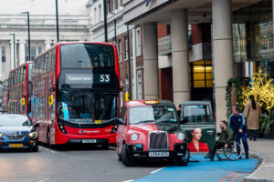 A taxi driver helps a person with a wheelchair get in a taxi , London, UK