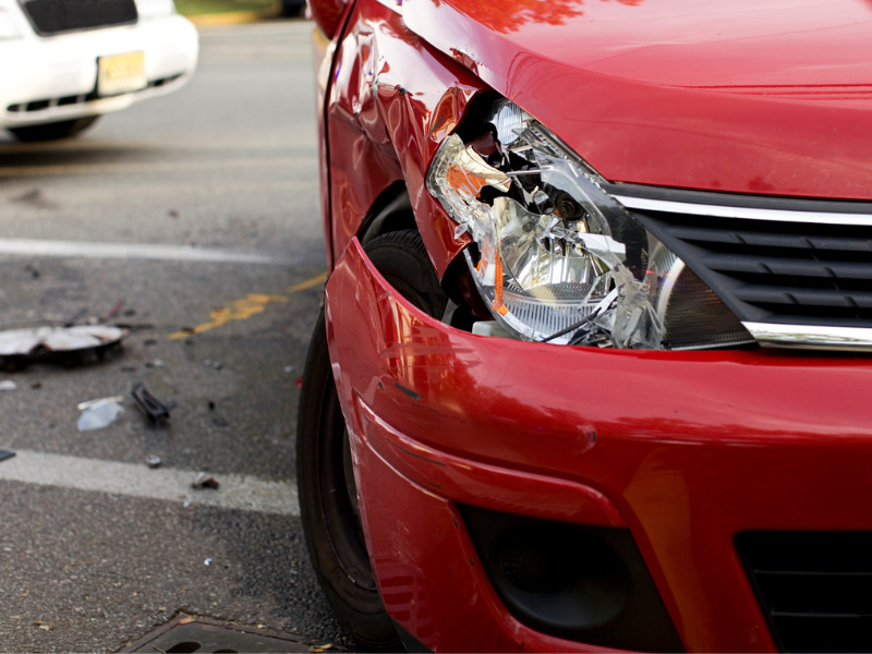 Red car with a damaged headlight after an accident
