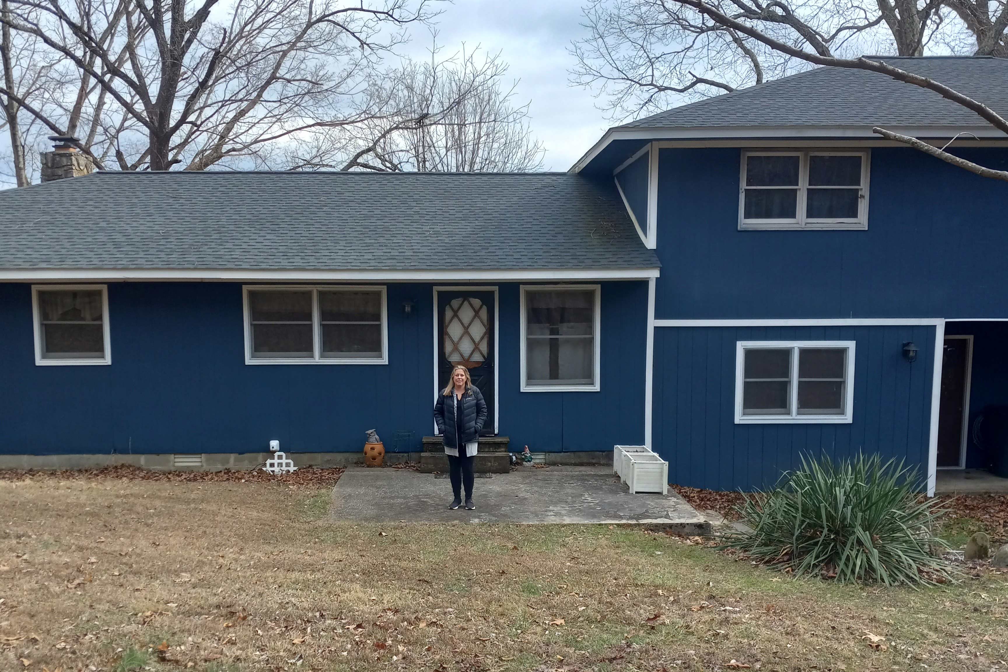 A photo of a woman standing in front of a house.