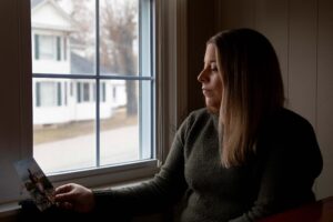 A photo of a woman holding a picture of her mother indoors.