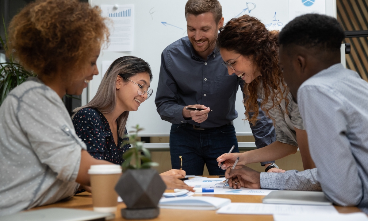 a group of employees gathered around a table looking at a bunch of papers