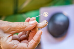 Close-up of senior woman holding a hearing aid.