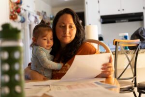 A photo of a mother holding her infant son while looking at medical bills.