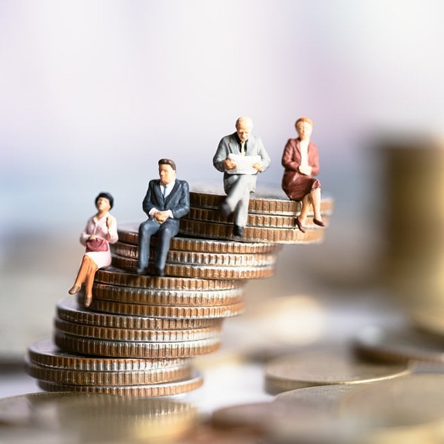 Miniature people sitting on a stack of coins