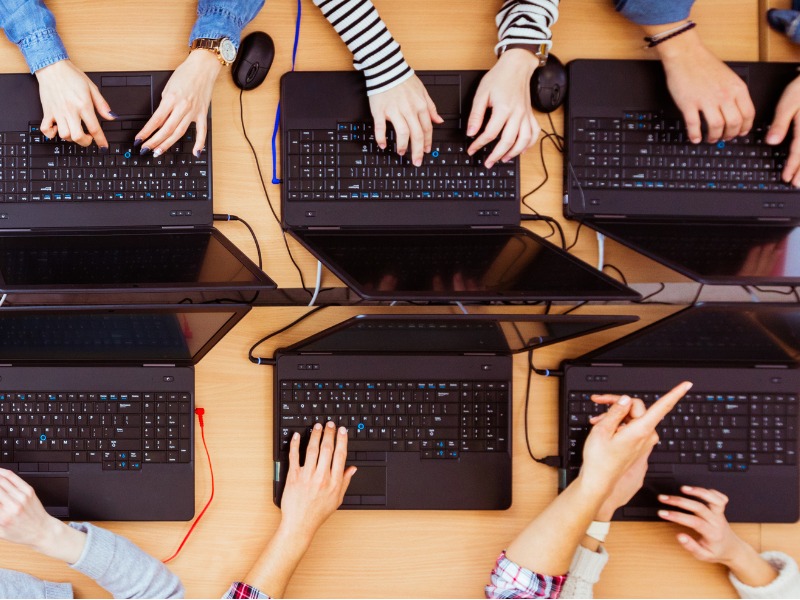 Top view of six cyber employees using laptops at a company