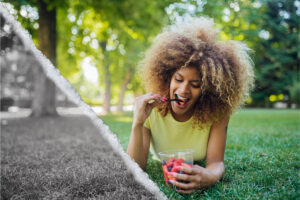 A woman enjoys a cup of fruit outdoors.