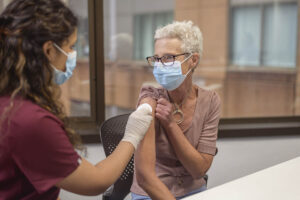 A mature woman is about to receive the shingles vaccine from a nurse