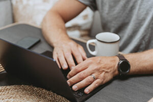 A close up photo of a man typing on a laptop.