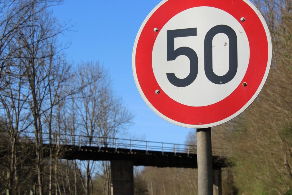 50 mph speed limit sign with trees in the background and a blue sky