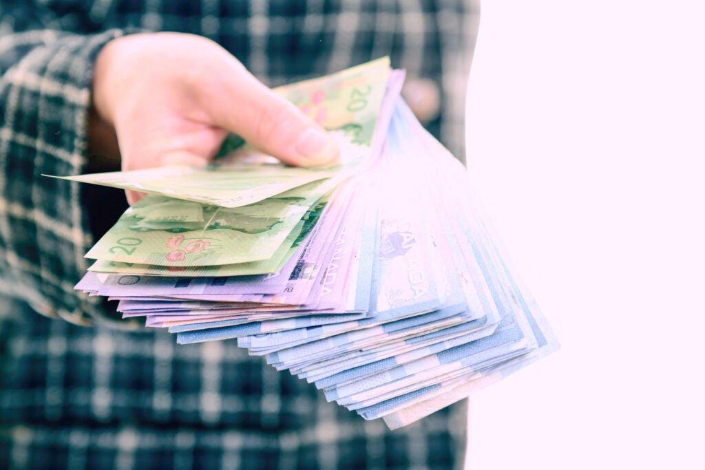 Person handing a stack of money toward the camera as a form of insurance salaries