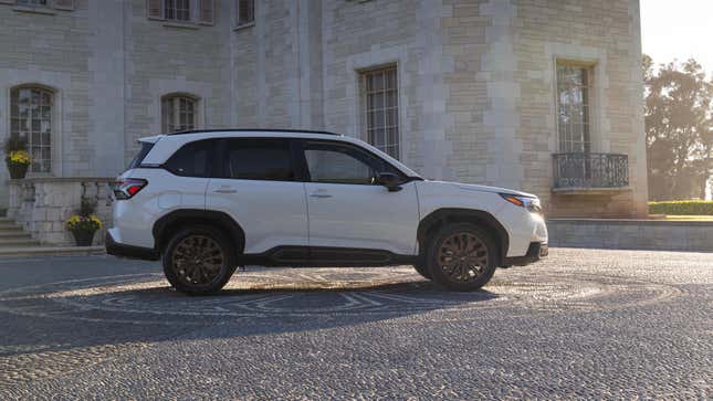 A white Forester from the side parked in front of a mansion