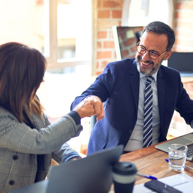 Two advisors fist bumping in celebration