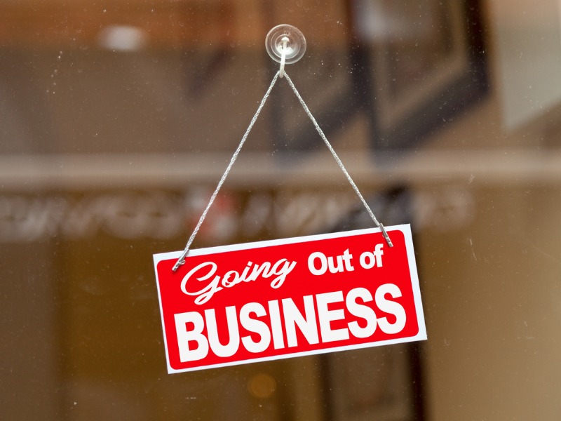 Red sign hanging at the glass door of a shop saying: "Going out of business"