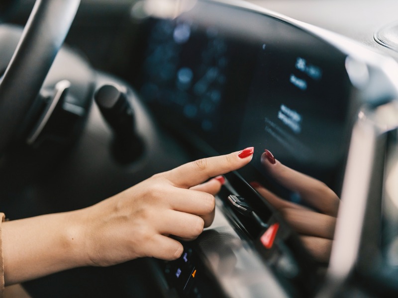 Close up of a female hand pressing touch screen in car