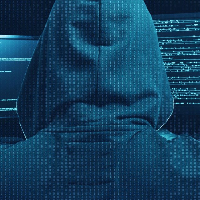 The rear view of a person in a hoodie, working on a computer.